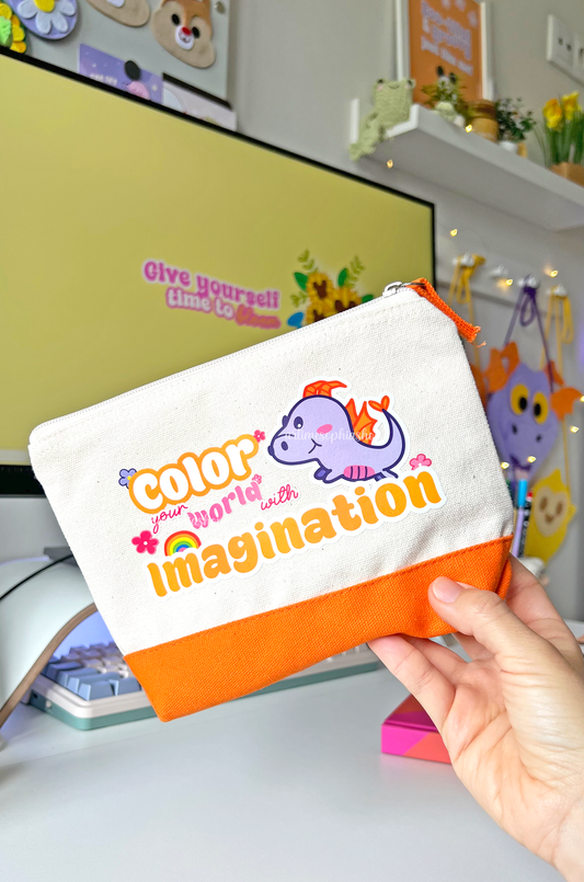 Cotton accessories pouch with a Figment illustration and the quote “Color Your World With Imagination”, featuring a bright orange stripe. Ideal for pens, pencils, and small creative items.