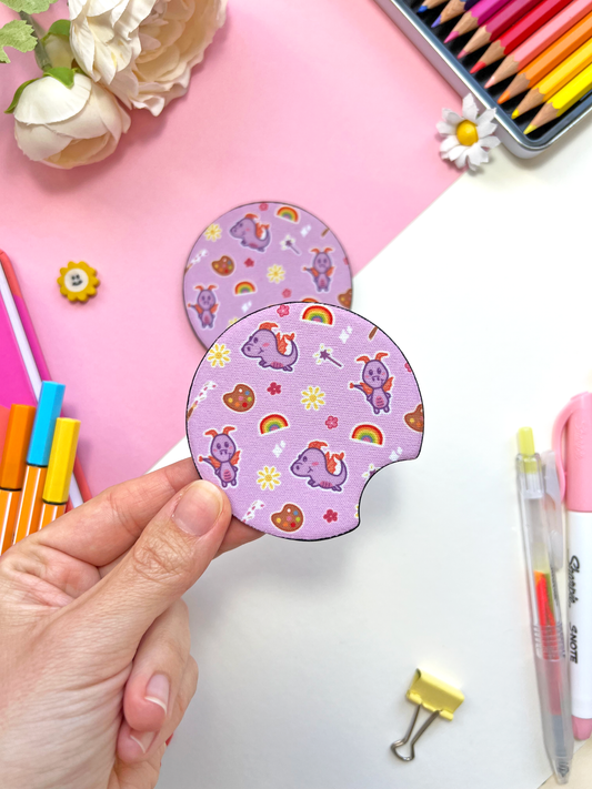 A set of two round neoprene car coasters featuring Figment the dragon with colourful art doodles on a soft lilac background.