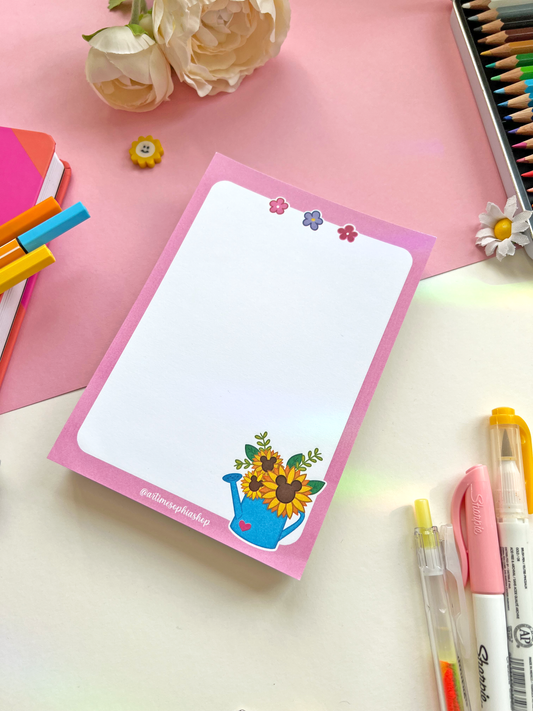 A6 notepad with a soft pink background and a sunflower-filled watering can, paired with the phrase “Give Yourself Time To Bloom” — ideal for notes or journaling.