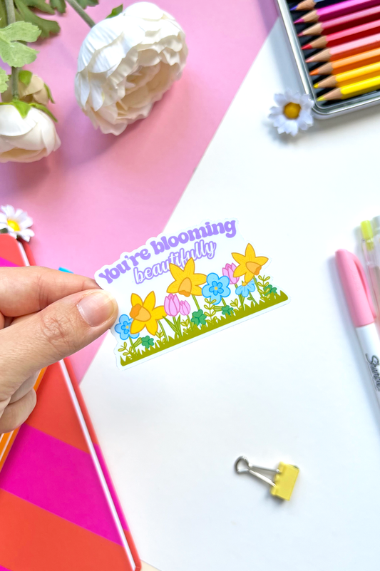 Waterproof vinyl sticker with pastel flowers and the uplifting message “You’re Blooming Beautifully” — perfect for journals, bottles, or laptops.
