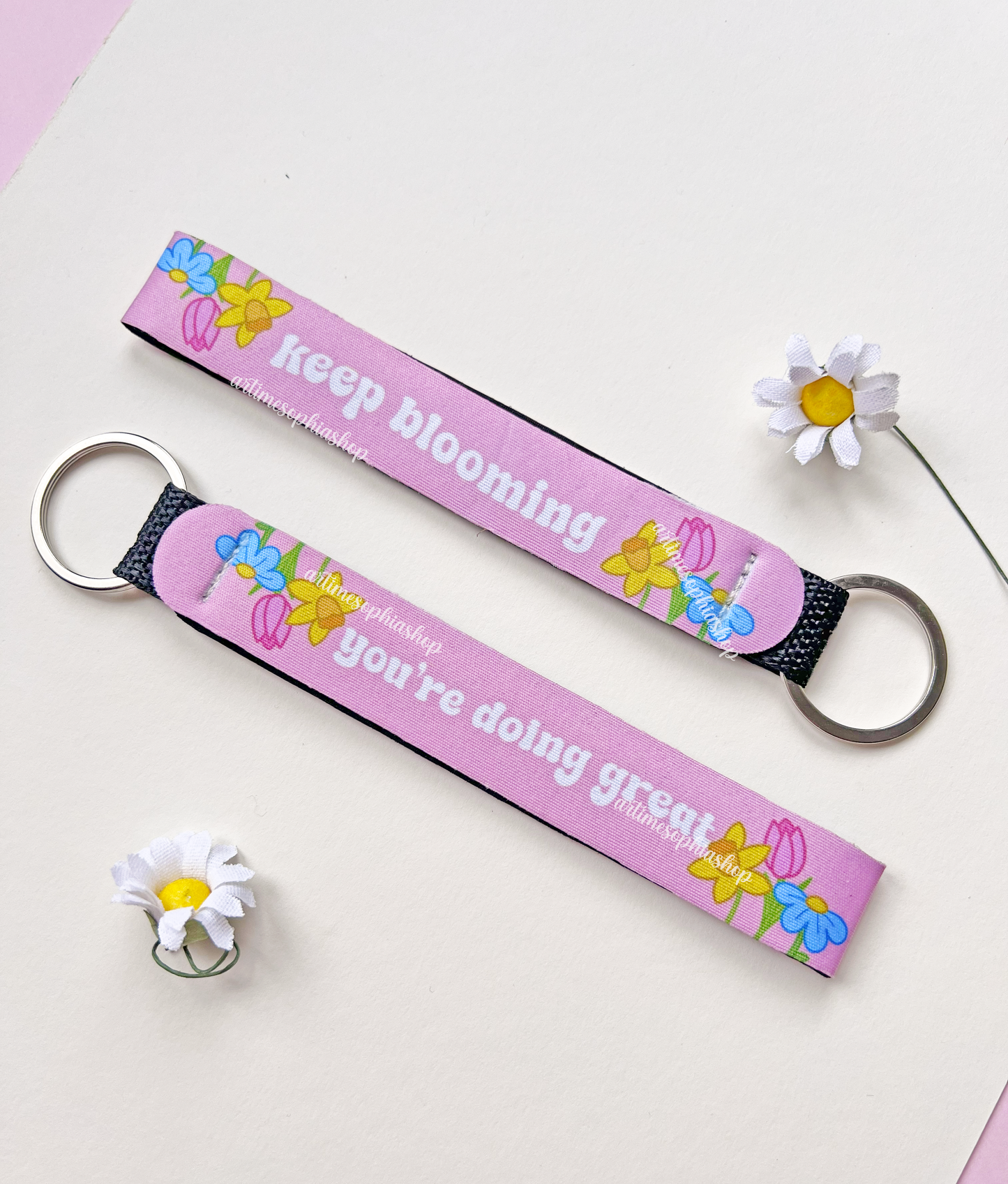 Pink floral wrist keychain with motivational quote on white background