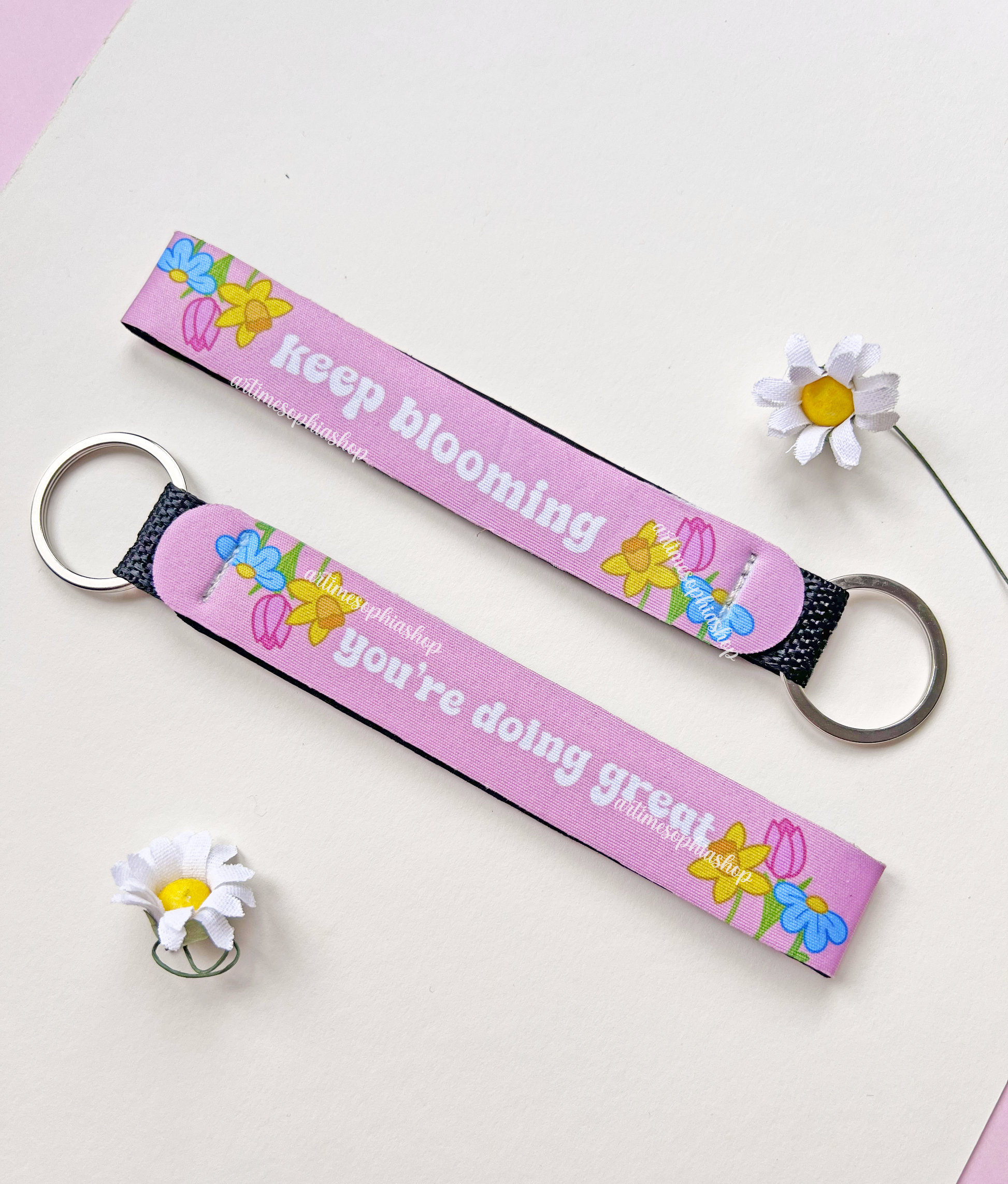 Pink floral wrist keychain with motivational quote on white background