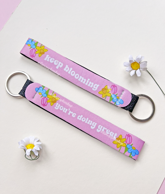 Pink floral wrist keychain with motivational quote on white background