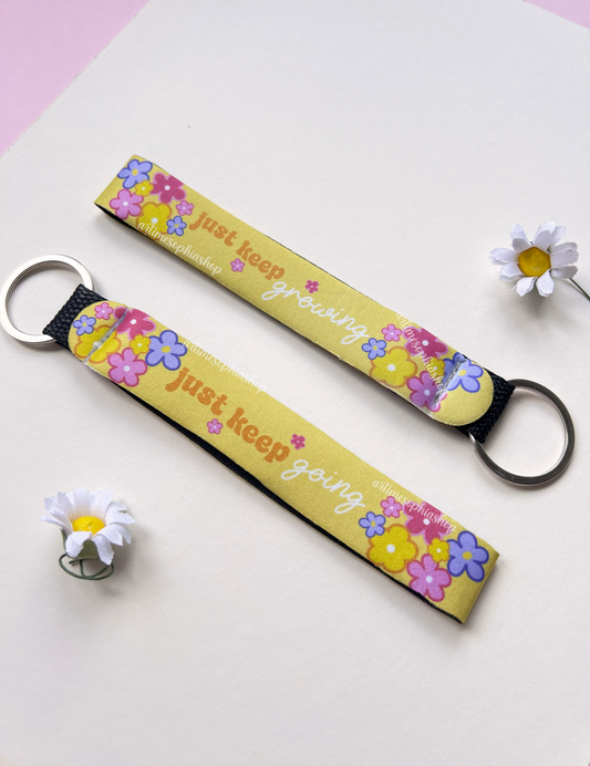 Yellow floral wrist keychain with motivational quote on white background