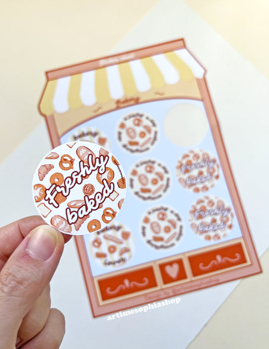 Large bakery-themed sticker sheet designed like a bakery storefront with nine round illustrated labels featuring bakery-inspired phrases.